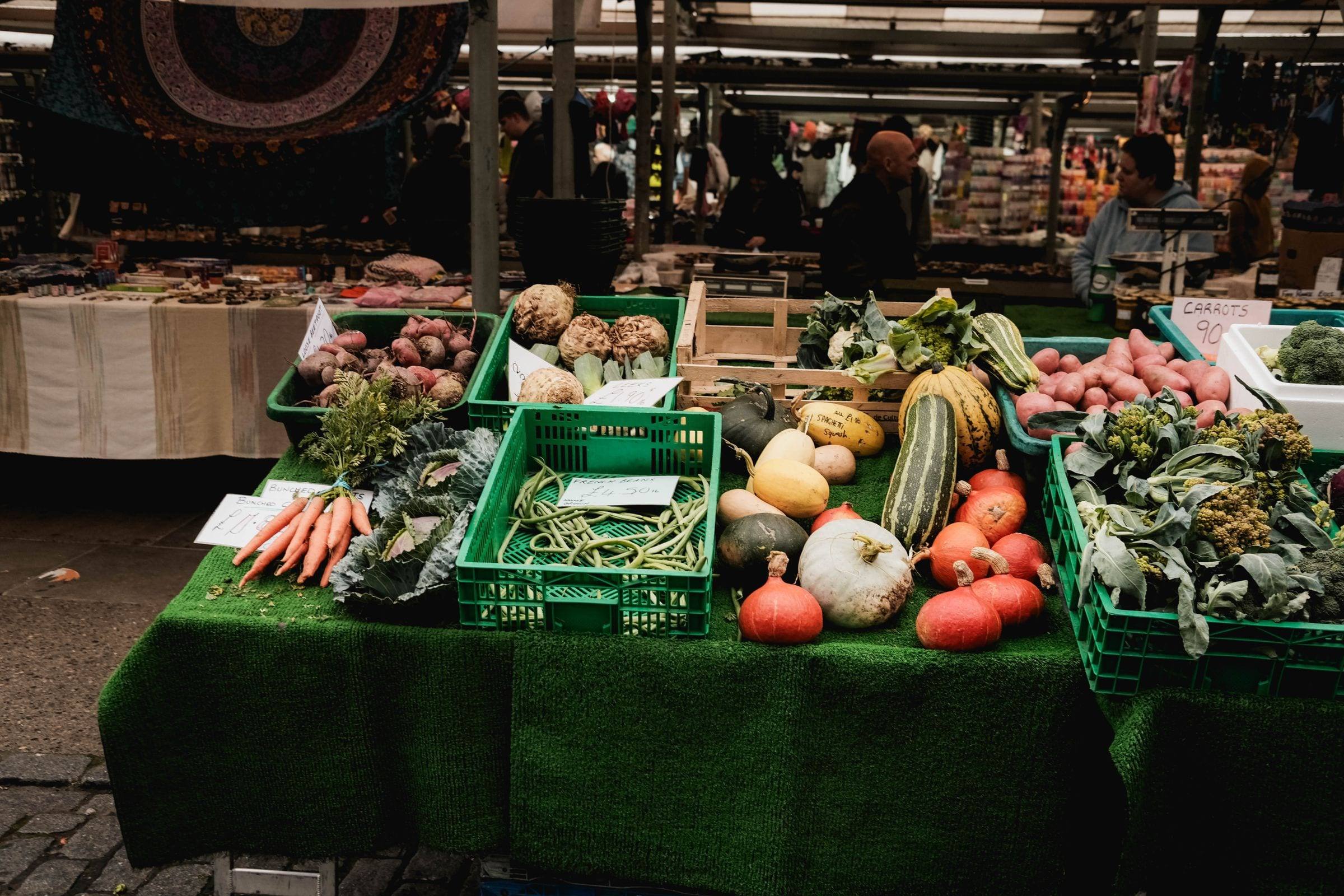Marktstand mit Kisten voller Kürbisse, Möhren, Kohl und anderem Gemüse