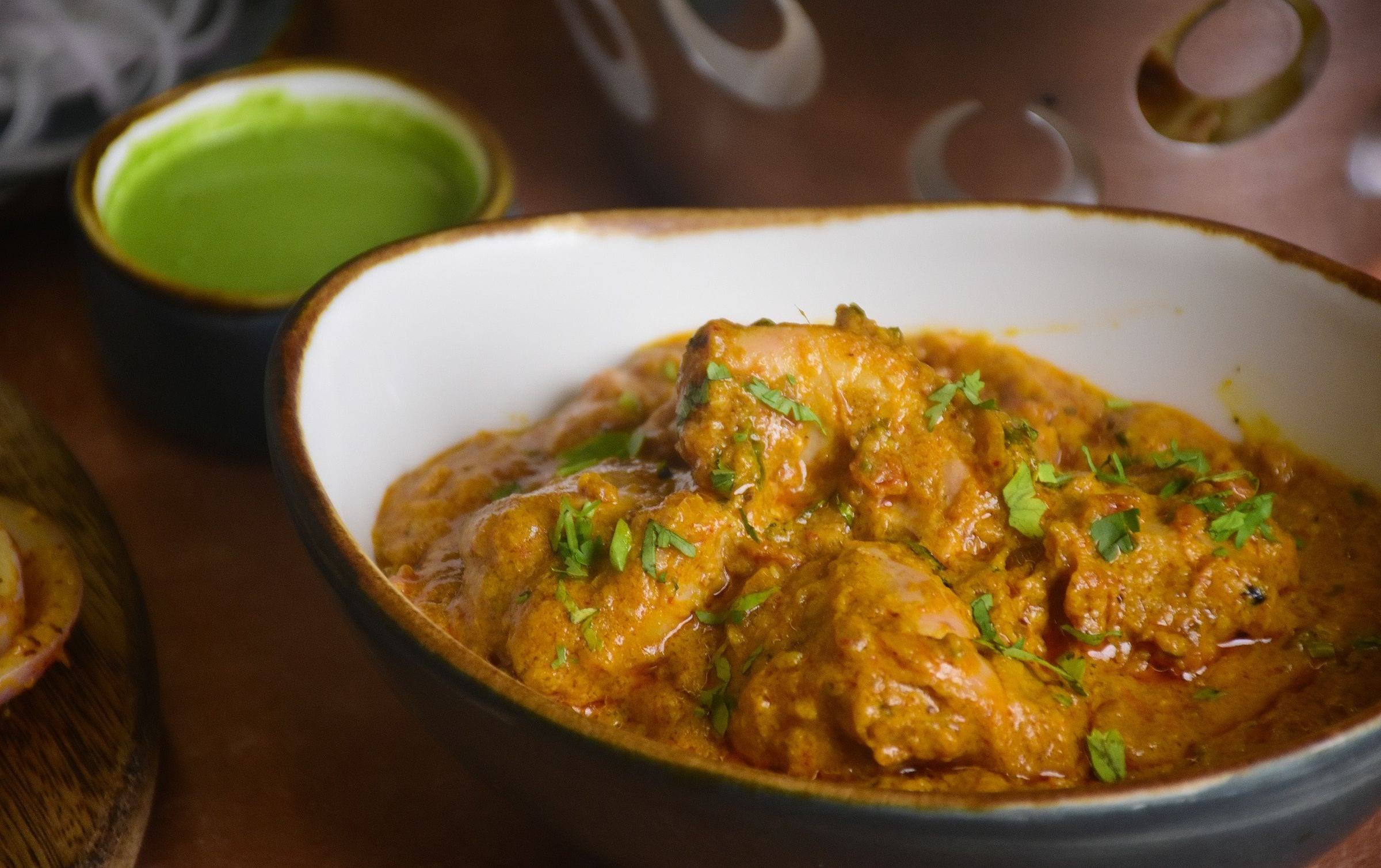 Hähnchencurry in orangefarbener Sauce mit Koriander in einer Schale