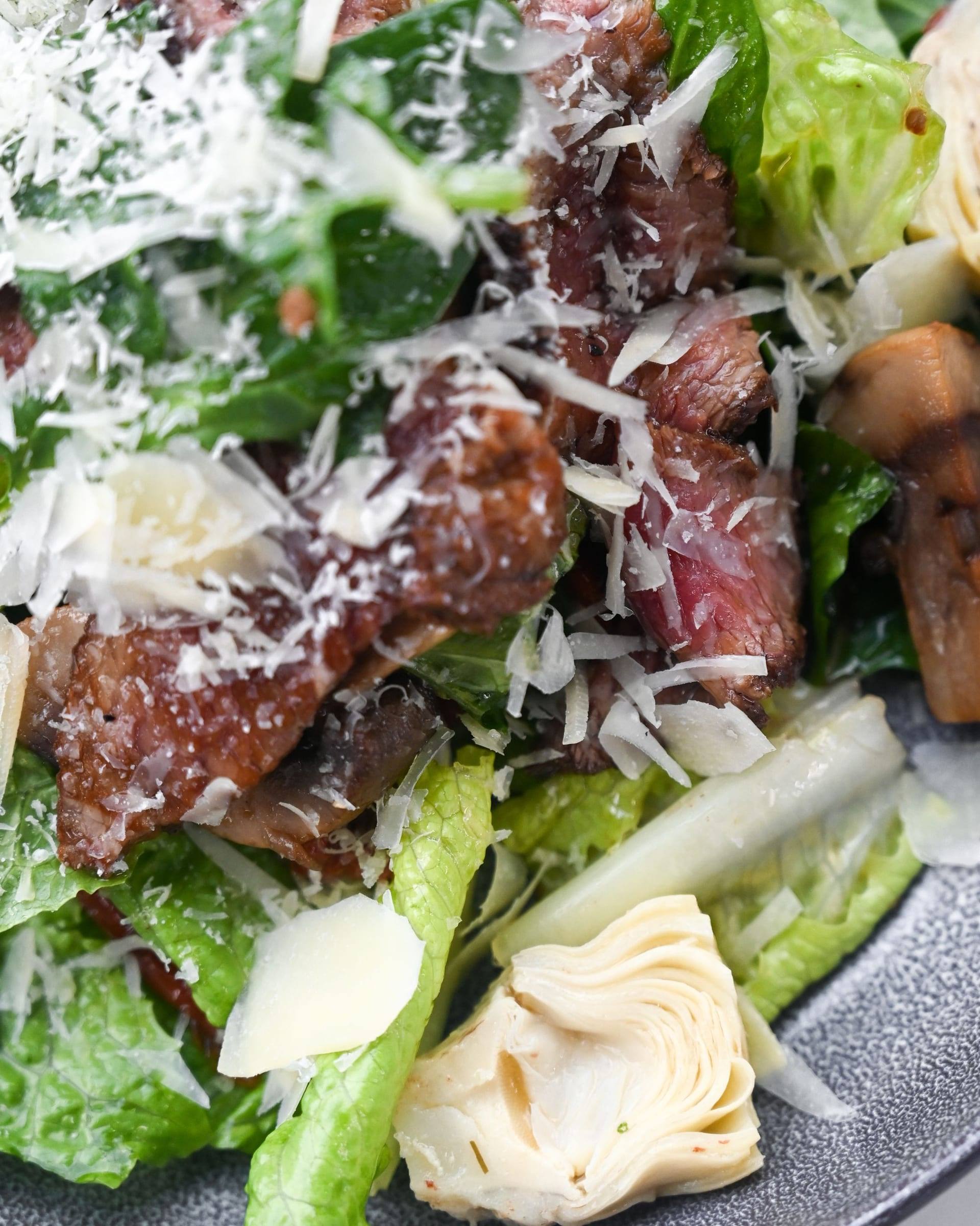 Salat mit gebratenen Rindfleischstreifen und gehobeltem Parmesan