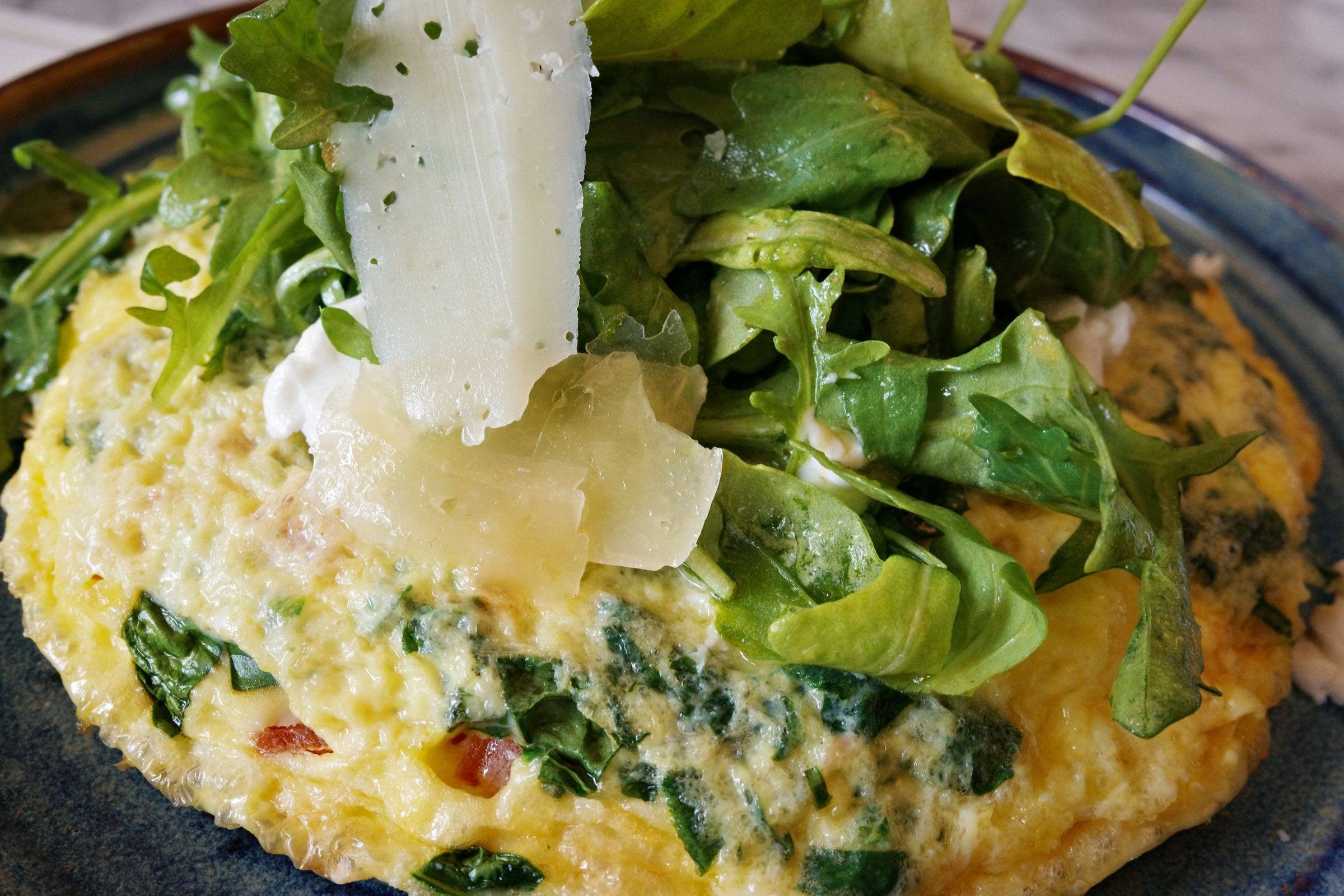 Frittata mit Rucola und gehobeltem Käse in Nahaufnahme