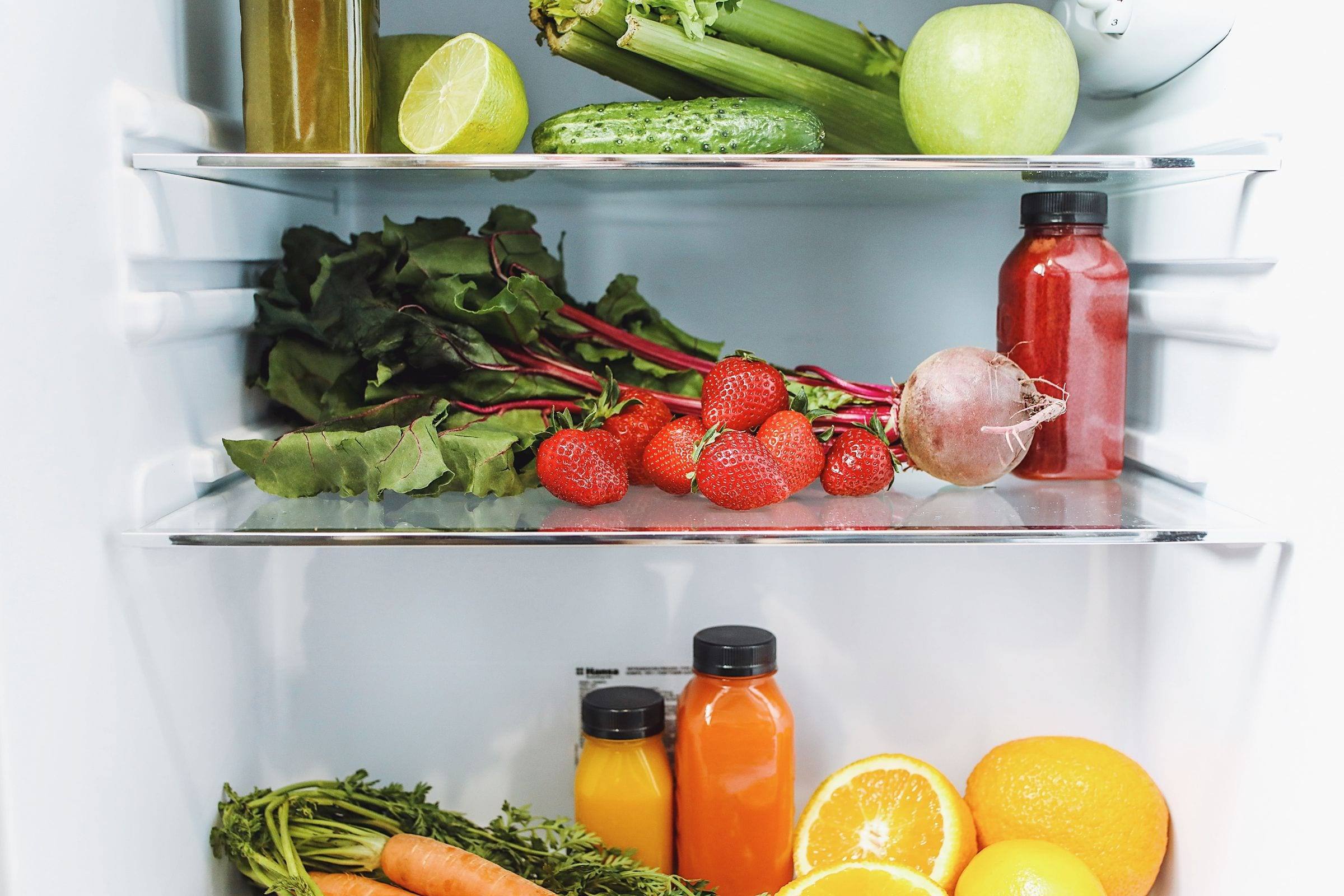 Geöffneter Kühlschrank mit Gemüse, Tomaten, Zitrusfrüchten und Säften in den Fächern