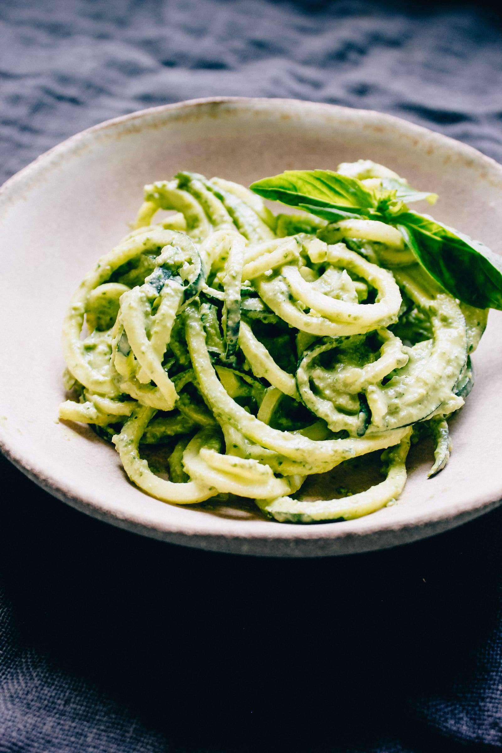 Zucchininudeln mit cremigem grünem Pesto in einer weißen Schale